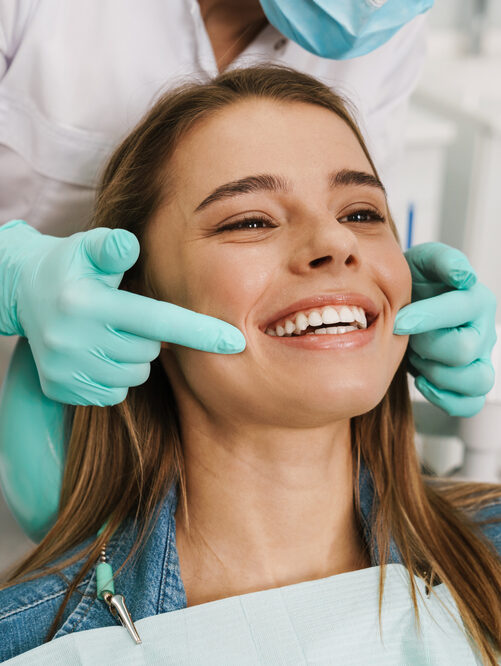 European,Young,Woman,Smiling,While,Looking,At,Mirror,In,Dental